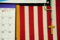 A rosary hangs on a flag near a calendar Sept. 28, 2016 at The Veterans Group in Philadelphia, Pa. The non-profit is committed to promoting the health and well-being of former armed forces service members.